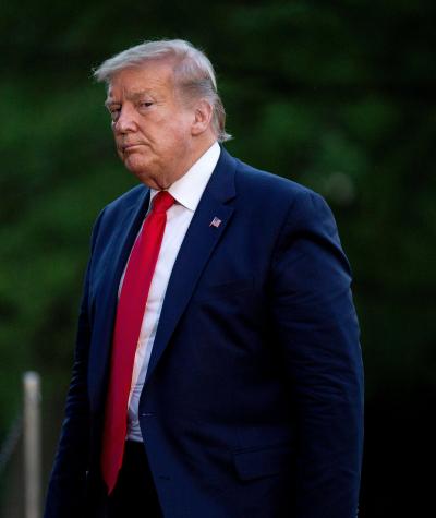 Donald Trump walking with trees in the background