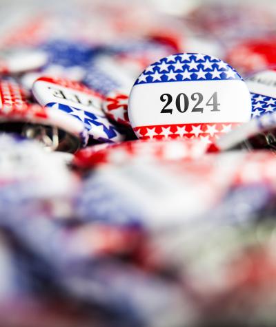 A pile of buttons with stars and stripes on them. One button in focus says "2024"